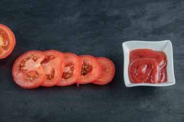 Koyu arkaplanda ketçaplı domates dilimleri.