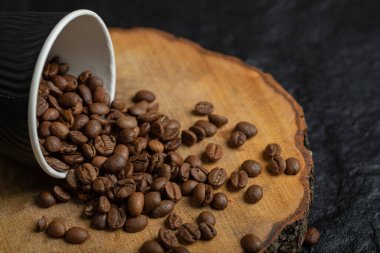 Tahtada kahve çekirdeği dolu siyah bir fincan.