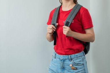 Omuzlarında gri bir sırt çantası olan okul çocuğu.