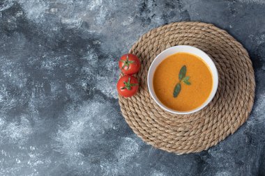 Beyaz bir kâse mermer kaplı domatesli mercimek çorbası.