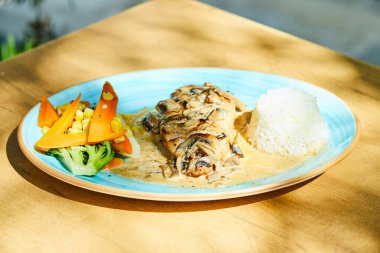 Kızarmış balık, pilav ve mavi tabakta sebze.