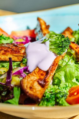 Sebze ve tavuk salatasını mavi tabağa koy.