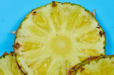 Mavi arka planda olgun ananas dilimleri