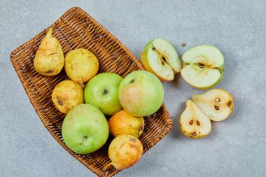 Elmalar ve armutlar gri arka planda sepete.