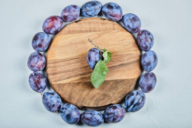 Tahta tabağın etrafında bir grup taze erik.