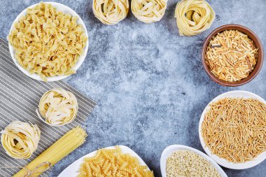 Mavi arka planda bir demet çiğ makarna kasesi.