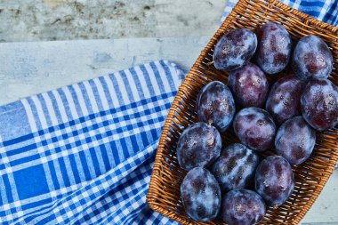 Bahçe erikleri bir sepetin içinde, masa örtüsünün üzerinde.