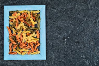 Koyu arkaplanda resim çerçevesinde çiğ renkli makarna