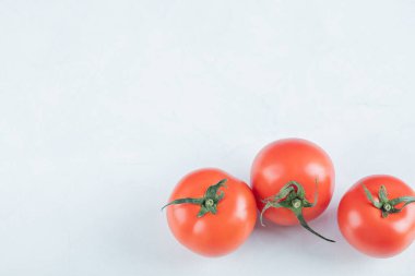 Beyaz arka planda üç tane taze domates.