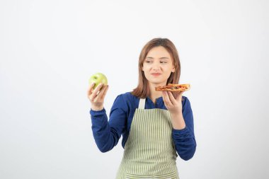 Önlüklü kadın portresi elma mı pizza mı yiyeceğini seçmeye çalışıyor.