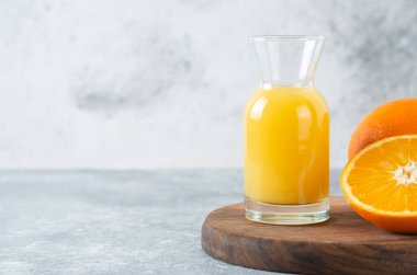 Ahşap bir tahtanın üzerinde dilimlenmiş portakal suyu dolu cam sürahi. Yüksek kalite fotoğraf