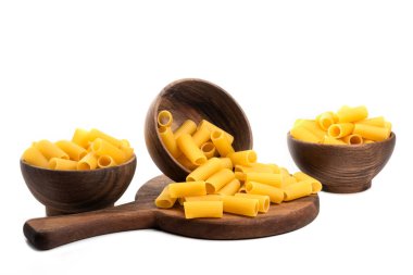 Ahşap kaseler, ahşap bir tahtanın üzerinde pişmemiş yumuşak, kısa tüplerle dolu makarna şeklinde. Yüksek kalite fotoğraf