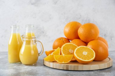 Taş zemin üzerinde taze portakal meyveleri olan cam bir sürahi meyve suyu. Yüksek kalite fotoğraf