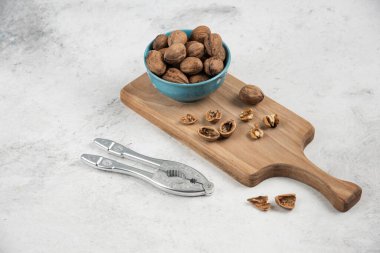 Ahşap kesme tahtasının üzerinde mavi bir kase dolusu ceviz. Yüksek kalite fotoğraf