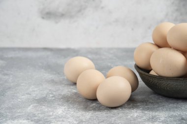 Esmer arka planda pişmemiş yumurta kasesi.