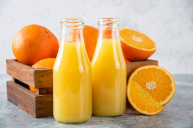 Taş zeminde taze portakal meyveleri olan cam bir sürahi meyve suyu.