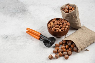 Bir kase organik fındık çekirdeği ve mermer arka planda kabuklu fındık.