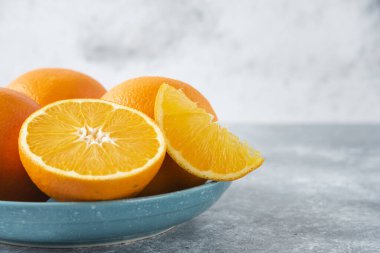 Taş zeminde dilimlenmiş ve sulu portakal meyveleriyle dolu bir tabak.