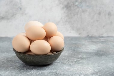 Esmer arka planda pişmemiş yumurta kasesi.