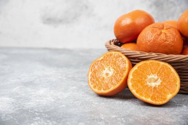 Taş zeminde sulu portakal meyveleriyle dolu bir hasır kutu.