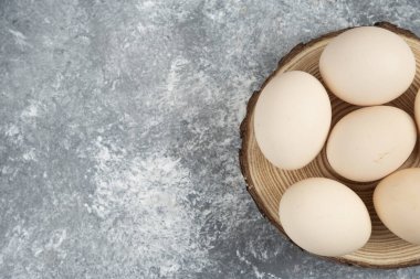 Tahta parçasına yerleştirilmiş taze pişmemiş organik yumurta yığını.