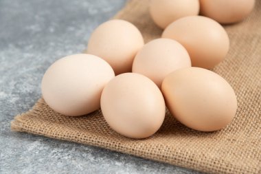 Mermer yüzeyinde masa örtüsü olan pişmemiş organik yumurta yığını.