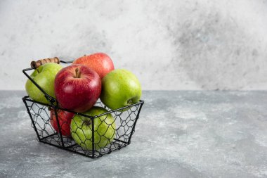 Metal sepete yerleştirilmiş taze yeşil ve kırmızı elmalar.