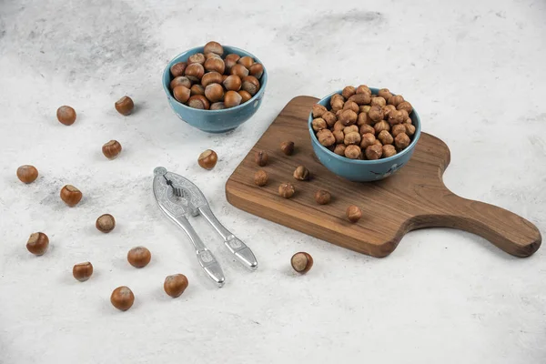 İki mavi kase kabuklu fındık ve mermer zemin üzerinde çekirdekler