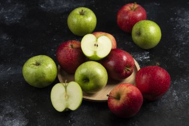 Tam ve dilimlenmiş yeşil ve kırmızı elmalar ahşap tabakta