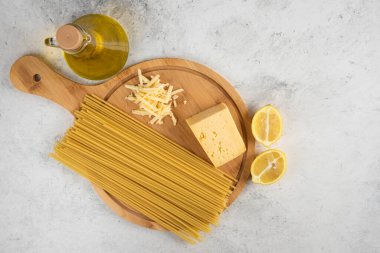 Çiğ spagetti, yağ, limon ve peynir beyaz masada.