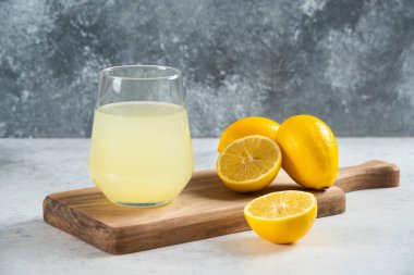 Tahtanın üzerinde bir bardak taze limon suyu.