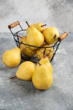 Mermer yüzeyde metal kovada taze sarı armutlar.