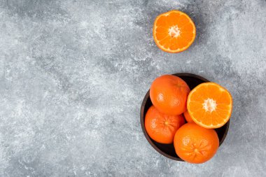 Taş zeminde sulu portakal meyveleriyle dolu ahşap bir kase.