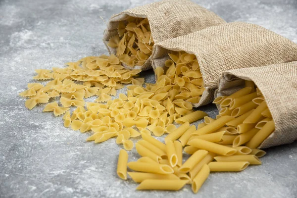 Tagliatelle makarnası ve kahverengi ahşap masada sarmal İtalyan makarnası.