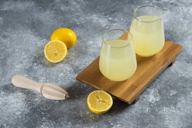 Limon dilimleri ve ahşap kabıyla dolu bardaklar dolusu limonata.