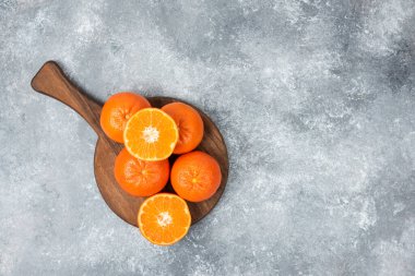 Taş zeminde dilimleri olan sulu portakal meyveleriyle dolu tahta bir tahta.