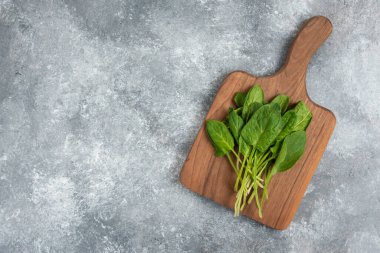 Mermer zemin üzerinde taze, sağlıklı yeşil yapraklardan oluşan ahşap tahta bir tahta.