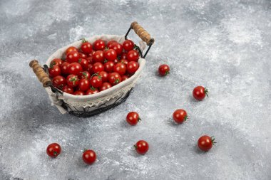 Kırmızı kiraz domatesleri mermer arka planda bir sepette