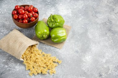 Çeri domatesli ve biberli, rustik bir poşette pişmemiş pizzalar.