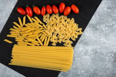 Çeşitli pişmemiş makarna ve domatesler.