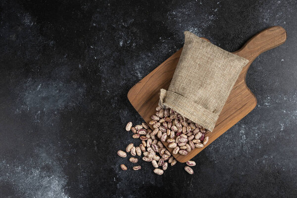 Sackcloth of dried raw beans placed on wooden board