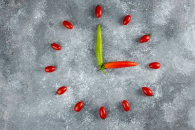 Domatesler ve biberler mermer yüzeyde saat gibi şekillenir.