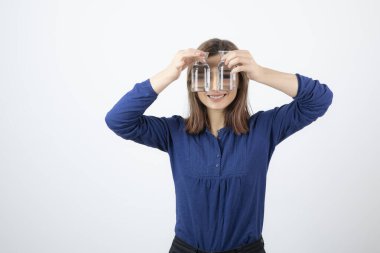 Mavi bluzlu genç kadın bir bardak su gösteriyor.