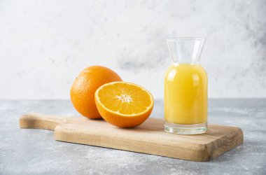 Tahtada dilimlenmiş portakal meyveli cam sürahi meyve suyu.