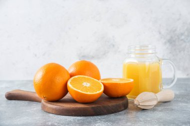 Taş zeminde taze portakal meyveleri olan cam bir sürahi meyve suyu.