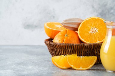 Taş zeminde sulu portakal meyveleriyle dolu bir hasır kutu.