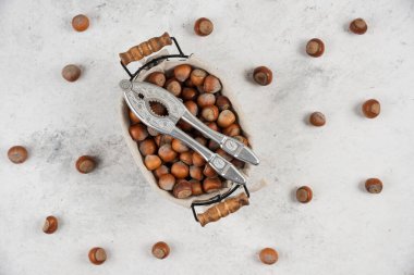 Bir sepet kabuklu fındık ve mermer zemin üzerinde fındık kırma aracı