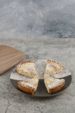 Tahtanın etrafına hindistan cevizi parçacıkları serpiştirilmiş lezzetli kek dilimleri. Yüksek kalite fotoğraf