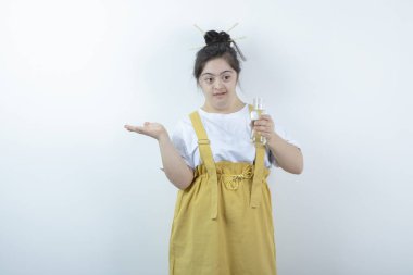 Genç ve güzel kız model ayakta ve beyaz duvara karşı cam şişe tutuyor. Yüksek kalite fotoğraf