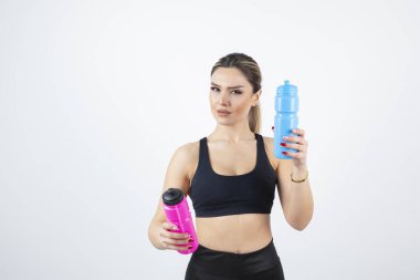 Mavi ve pembe su şişeleri tutan genç atletik kadın portresi. Yüksek kalite fotoğraf